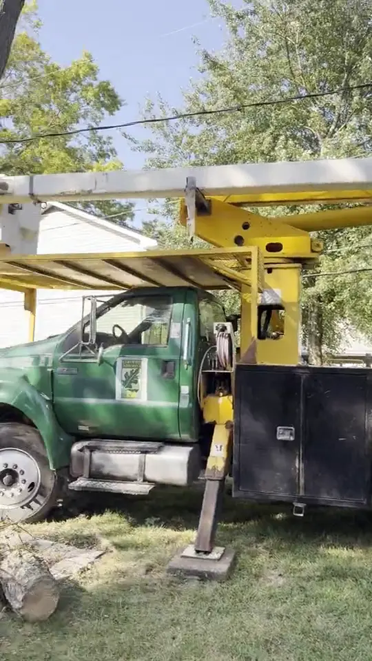 The green A.S.H. bucket truck set up on the lawn beside a house: tree removal by A.S.H. Tree Service, serving Pickerington, OH